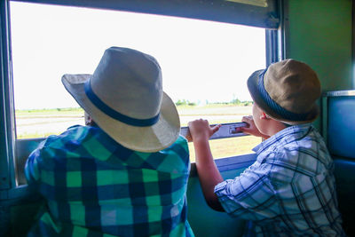 Rear view portrait of boys on car against sky