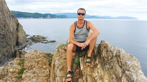 Man sitting on rock against sea