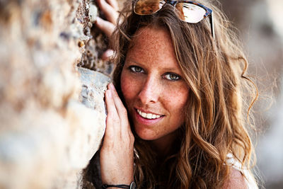 Portrait of smiling young woman by rock