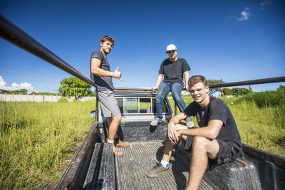 Three young men ride in the bed of 4x4 truck, rural central america.