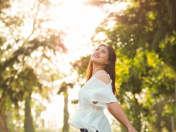 Beautiful young woman standing against tree