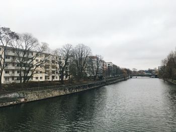 Bridge over river amidst buildings in city against sky