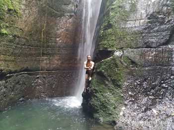 Man standing by waterfall in forest