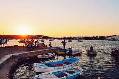 People on beach against clear sky during sunset