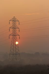 Low angle view of silhouette electricity pylon against sky during sunset