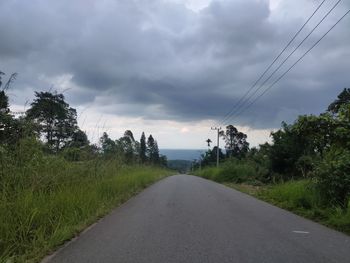 Road by trees against sky