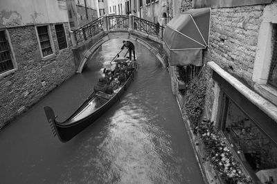 High angle view of people in gondola on canal amidst buildings