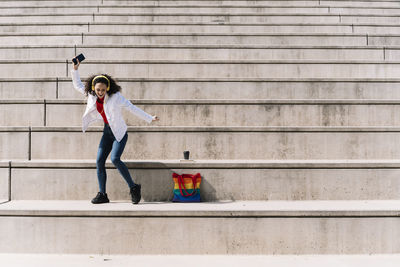 Full length of woman holding umbrella against wall