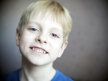 Close-up portrait of smiling boy against wall
