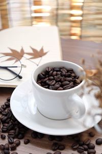 Close-up of roasted coffee beans in cup on table