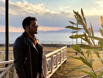 Man looking away while standing against sky during sunset