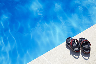 High angle view of shoes by swimming pool against sea