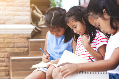 Girls studying while sitting on chair