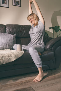Full length of woman relaxing on sofa at home