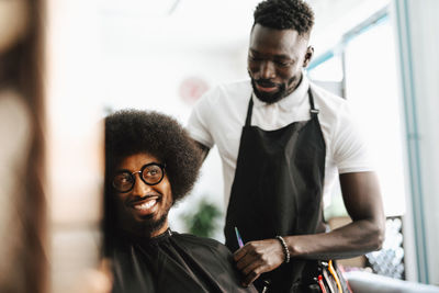 Smiling male customer talking with barber in hair salon