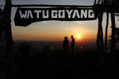 Silhouette people by sea against sky during sunset