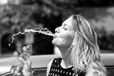 Close-up of woman spitting water during sunny day