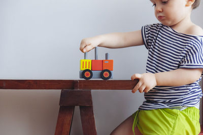 Midsection of boy playing with toy car on table at home