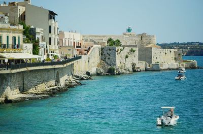 Boats in sea against buildings in city
