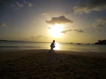 Man standing on beach against sky during sunset