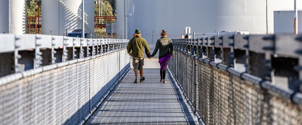 Rear view of people walking on bridge