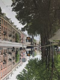 Canal by buildings in city against sky