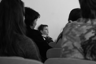 Rear view of mother and daughter sitting on sofa