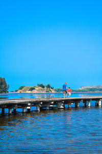 Pier over lake against clear blue sky