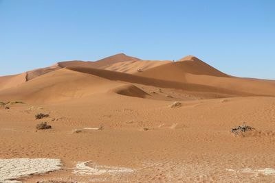 Sand dunes in desert against clear blue sky