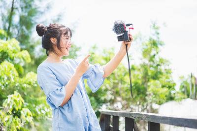 Woman photographing with mobile phone standing outdoors