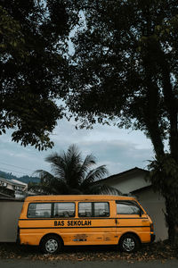 Cars parked by trees against sky in city