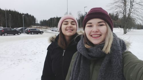 Portrait of smiling young woman in snow against sky