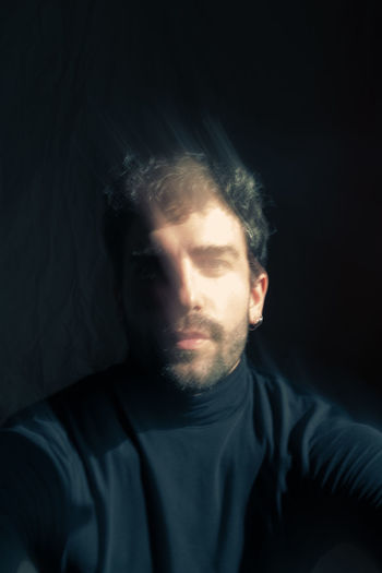 PORTRAIT OF YOUNG MAN WEARING BLACK BACKGROUND