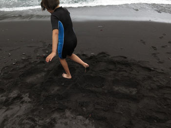 Full length of girl playing in sand on beach