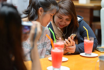 Woman using mobile phone while sitting on table