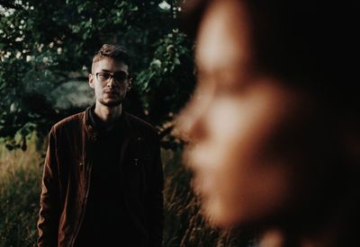 Portrait of young man standing against trees