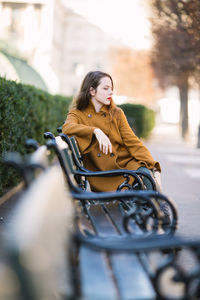 Young woman wearing coat sitting on the bench