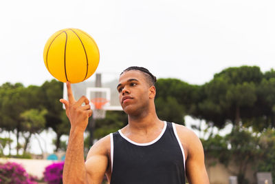 Concentrated african american basketball player spinning ball on finger during training on playground