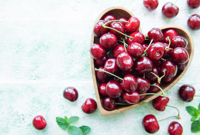 Fresh red cherries fruit in bowl on a wooden background