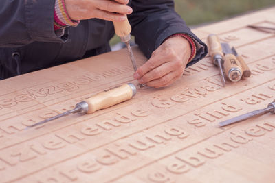 Cropped hand carving texts on wooden plank