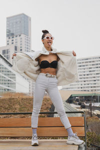 Fashionable woman standing against buildings in city