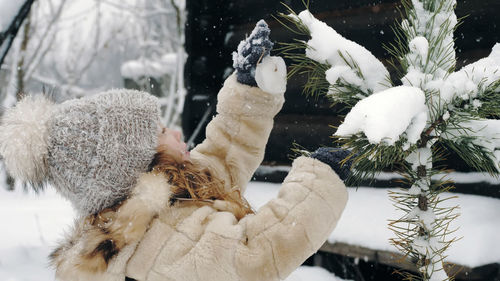 Christmas tree outdoor decoration. cutie, pretty little girl decorates snow-covered christmas tree