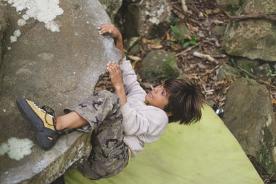 Little boy climbing a rock outdoors