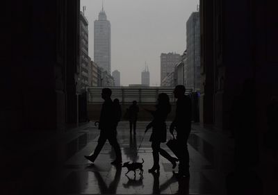 People walking in corridor of building against sky in city