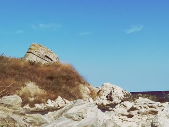 Rocks on land against blue sky