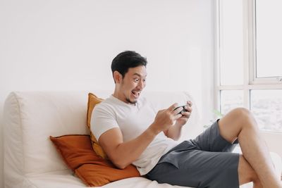 Young woman using mobile phone while sitting on bed at home