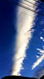 Low angle view of electricity pylon against blue sky