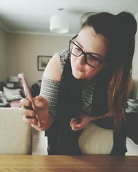 Young woman using mobile phone while sitting on table