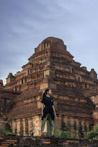 Low angle view of woman standing in front of historic building