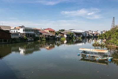 Buildings by river against sky